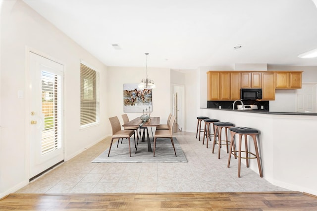 dining space featuring sink, a notable chandelier, and light wood-type flooring