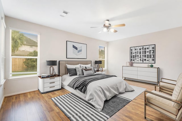 bedroom featuring ceiling fan, light hardwood / wood-style floors, and multiple windows