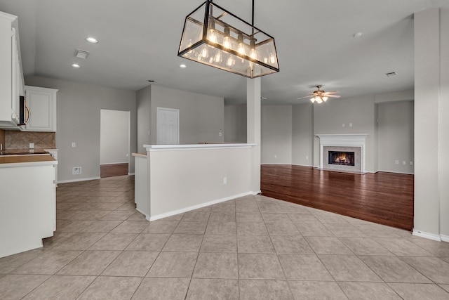 interior space with a fireplace, light tile patterned floors, and ceiling fan