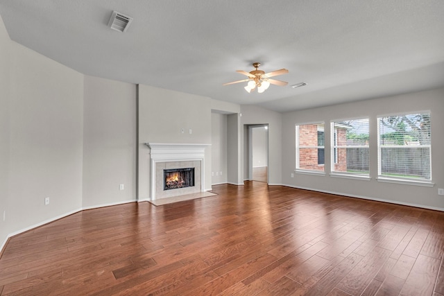 unfurnished living room with a tile fireplace, dark hardwood / wood-style floors, and ceiling fan