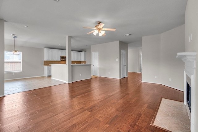 unfurnished living room featuring ceiling fan and light hardwood / wood-style floors