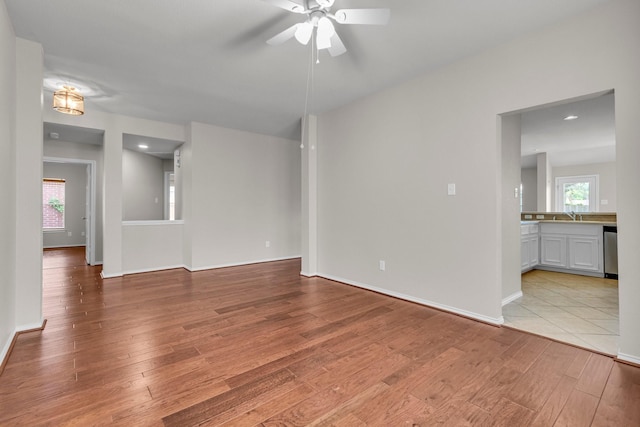 spare room with a wealth of natural light, ceiling fan, and light hardwood / wood-style floors