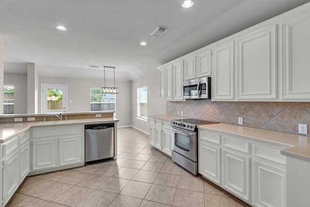 kitchen featuring white cabinetry, sink, stainless steel appliances, decorative light fixtures, and decorative backsplash