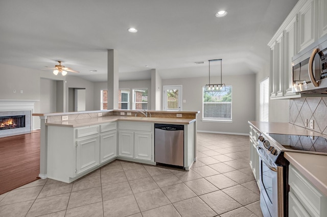 kitchen with hanging light fixtures, light tile patterned floors, decorative backsplash, white cabinets, and appliances with stainless steel finishes