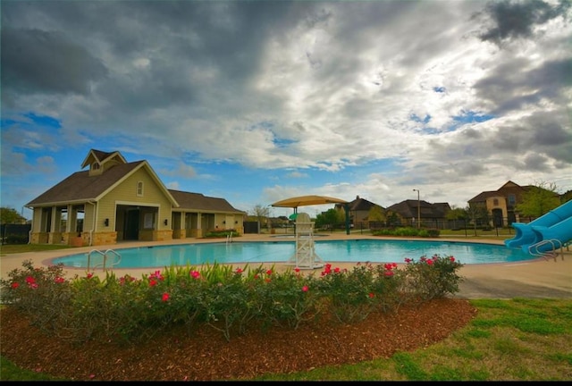 view of swimming pool with a water slide and a patio