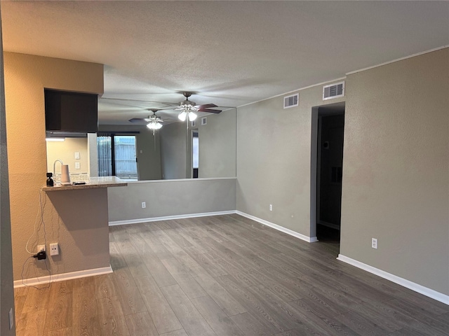 unfurnished living room featuring ceiling fan and dark wood-type flooring