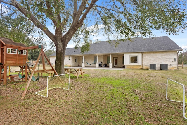 back of property featuring central AC unit, a playground, a patio, and a yard