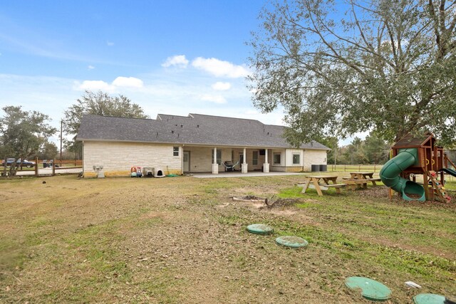 back of property featuring a playground, a lawn, and a patio