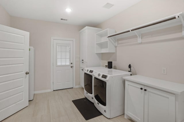 washroom with washer and dryer and cabinets