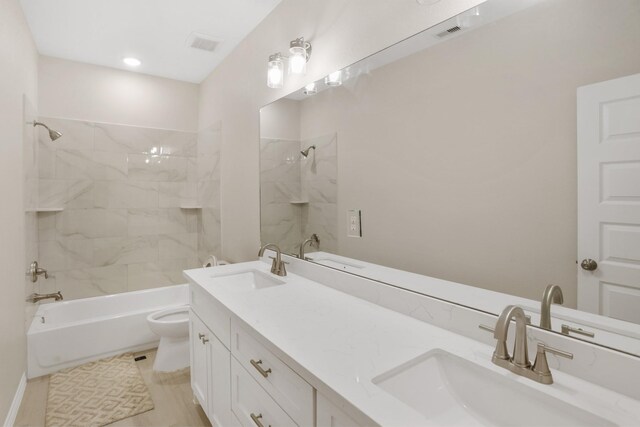 full bathroom featuring vanity, tiled shower / bath combo, and toilet