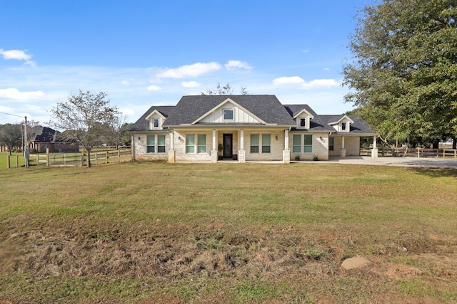 view of front of property with board and batten siding, a front lawn, and fence