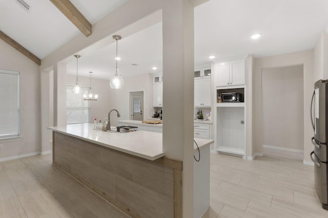 kitchen featuring white cabinets, pendant lighting, a center island with sink, and stainless steel fridge