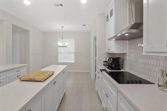 kitchen with hanging light fixtures, wall chimney range hood, black electric cooktop, decorative backsplash, and white cabinets