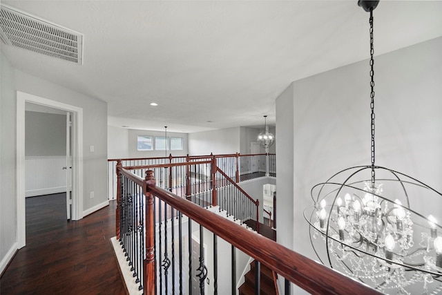 hall featuring an inviting chandelier and dark wood-type flooring