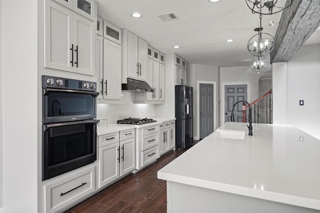 kitchen featuring hanging light fixtures, double oven, refrigerator, a chandelier, and white cabinets