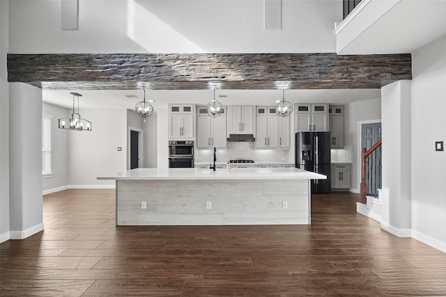 kitchen featuring backsplash, hanging light fixtures, a spacious island, and black appliances