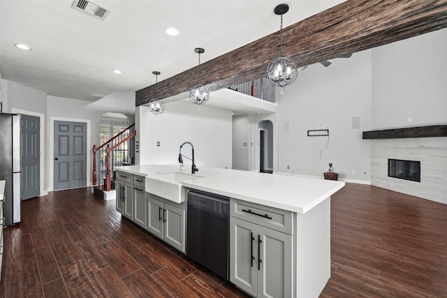 kitchen featuring sink, hanging light fixtures, black dishwasher, gray cabinets, and a fireplace