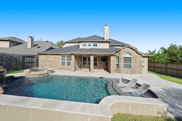 back of house with a patio area and a swimming pool with hot tub