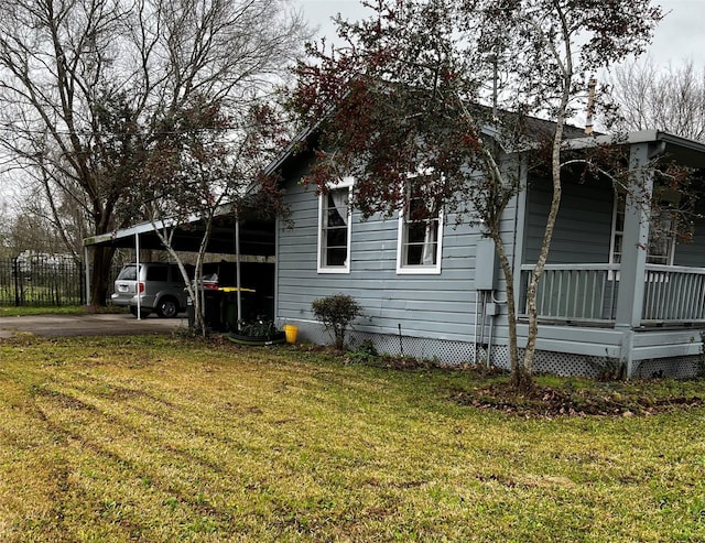 view of home's exterior with covered porch, driveway, an attached carport, and a lawn