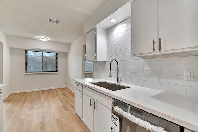 kitchen featuring backsplash, sink, light hardwood / wood-style flooring, dishwasher, and white cabinets