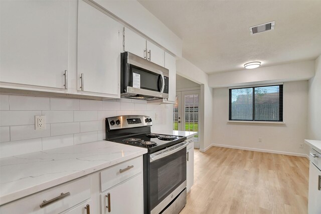 kitchen featuring white cabinets, light hardwood / wood-style flooring, decorative backsplash, light stone counters, and stainless steel appliances