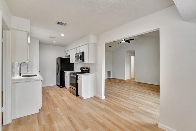 kitchen featuring sink, stainless steel appliances, tasteful backsplash, white cabinets, and light wood-type flooring