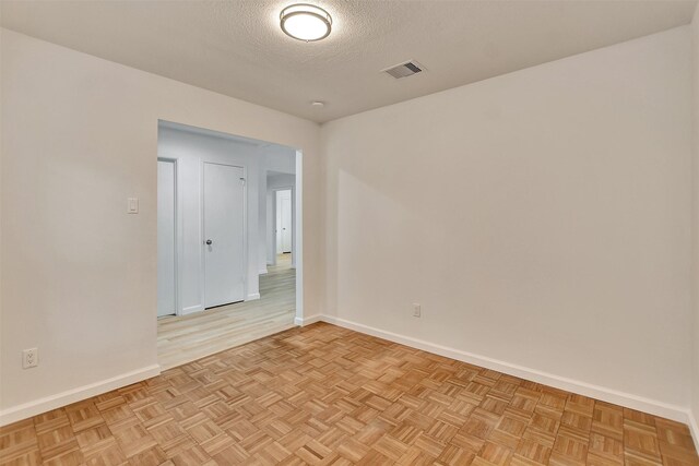 empty room with light parquet floors and a textured ceiling