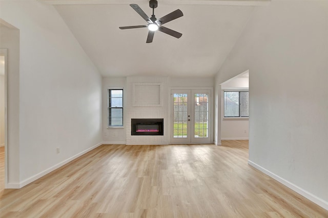 unfurnished living room with french doors, ceiling fan, high vaulted ceiling, a fireplace, and light hardwood / wood-style floors