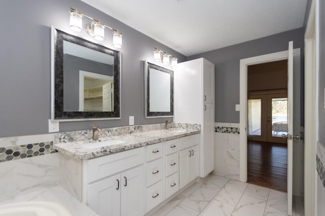 bathroom with french doors, vanity, and tile walls