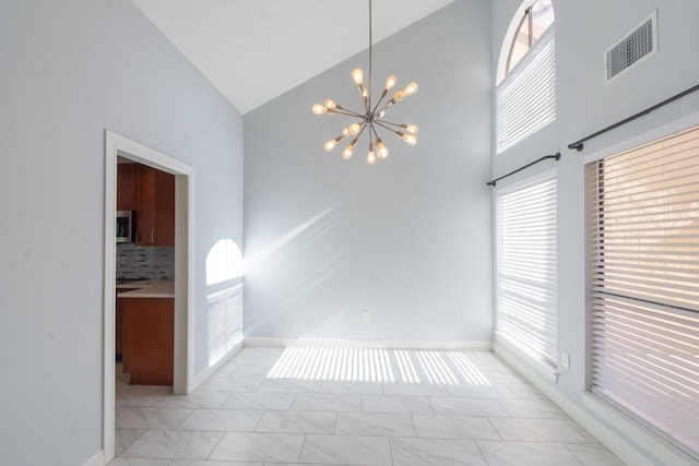 tiled spare room featuring high vaulted ceiling and an inviting chandelier