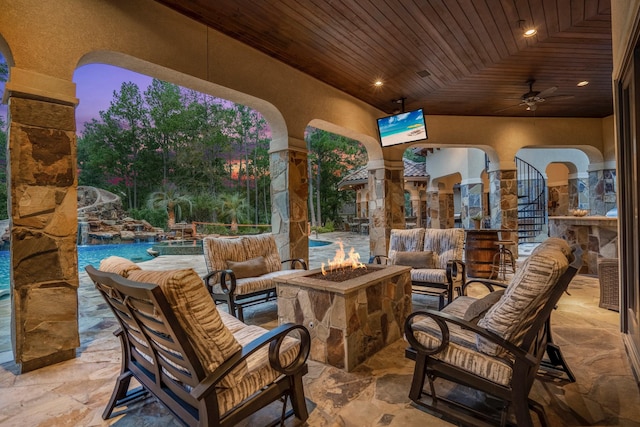 patio terrace at dusk featuring a fire pit and ceiling fan