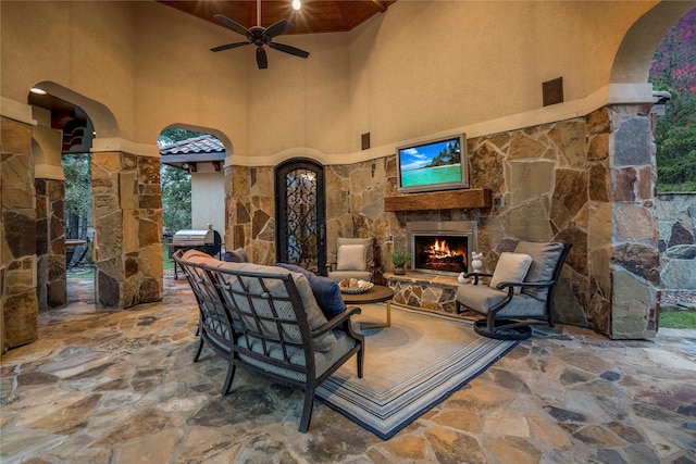 view of patio with an outdoor living space with a fireplace, ceiling fan, and a grill