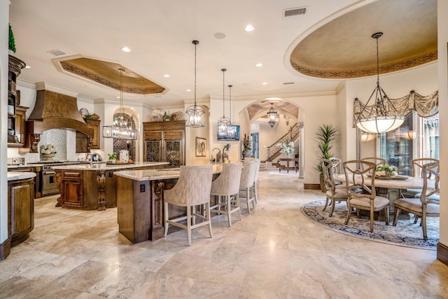 28322 Meadow Frst, Magnolia, TX 77355 - kitchen with a chandelier, premium range hood, a large island with sink, high end range, and arched walkways