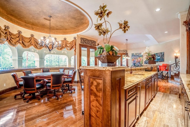 kitchen featuring light stone countertops, decorative light fixtures, a raised ceiling, and a chandelier