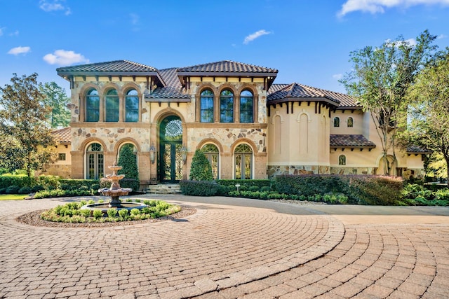 28322 Meadow Frst, Magnolia, TX 77355 - mediterranean / spanish-style home with curved driveway, stone siding, stucco siding, a tile roof, and french doors