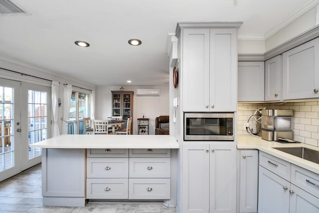 kitchen with a wealth of natural light, a wall mounted air conditioner, decorative backsplash, crown molding, and light hardwood / wood-style flooring