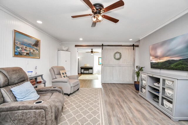 living room with ornamental molding, a barn door, and light hardwood / wood-style flooring