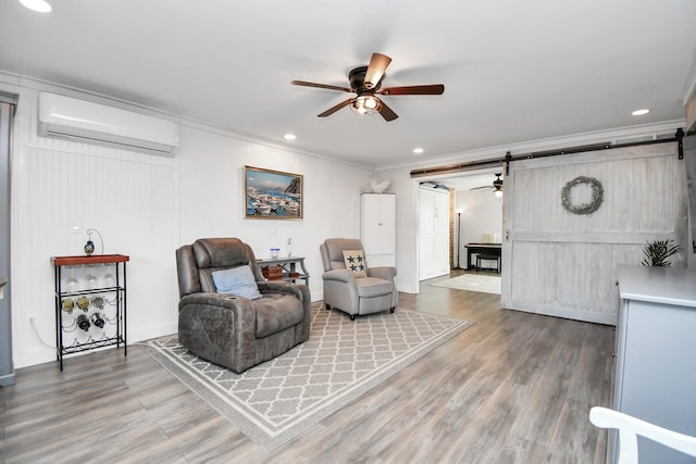 living room with hardwood / wood-style flooring, ornamental molding, ceiling fan, a barn door, and a wall unit AC