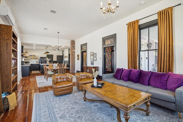 living room featuring a notable chandelier, an AC wall unit, and dark wood-type flooring