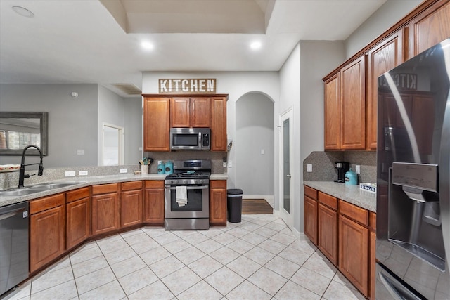 kitchen featuring light tile patterned flooring, sink, appliances with stainless steel finishes, and tasteful backsplash