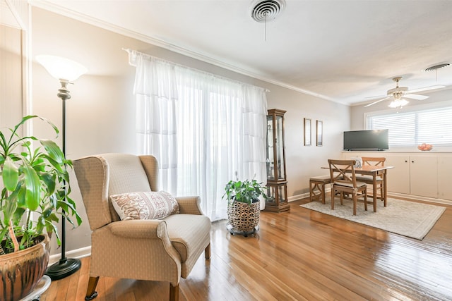 sitting room with hardwood / wood-style floors, ceiling fan, and ornamental molding