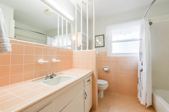 full bathroom with tile patterned floors, vanity, shower / bath combo with shower curtain, tile walls, and toilet