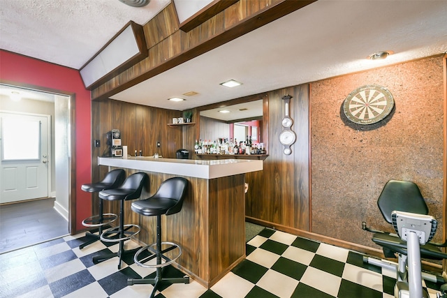 bar featuring wood walls and a textured ceiling