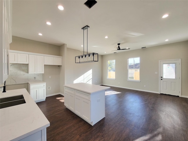 kitchen with tasteful backsplash, ceiling fan, decorative light fixtures, white cabinets, and a center island