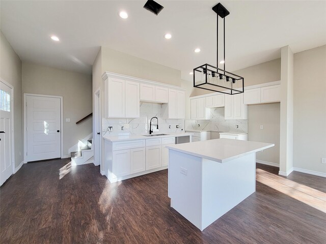 kitchen with washer and clothes dryer, white cabinetry, a center island, and sink