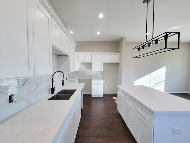 kitchen featuring decorative backsplash, white cabinetry, sink, and pendant lighting