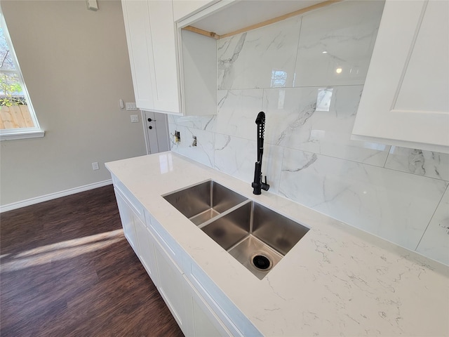 kitchen featuring white cabinetry, light stone countertops, sink, and dark wood-type flooring