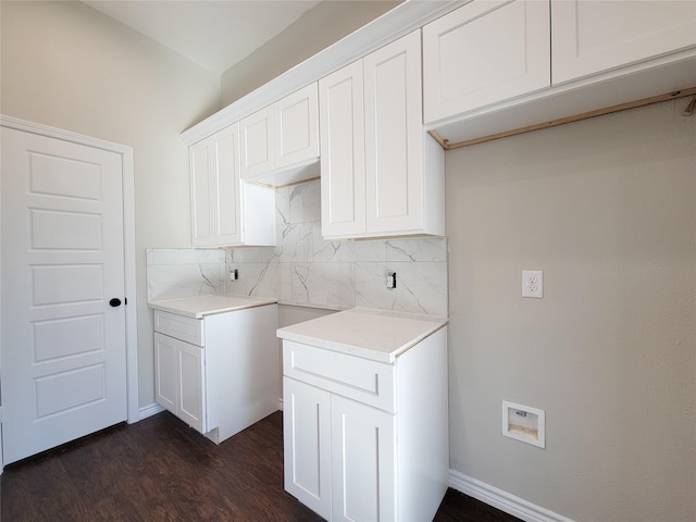 clothes washing area featuring dark hardwood / wood-style floors and cabinets