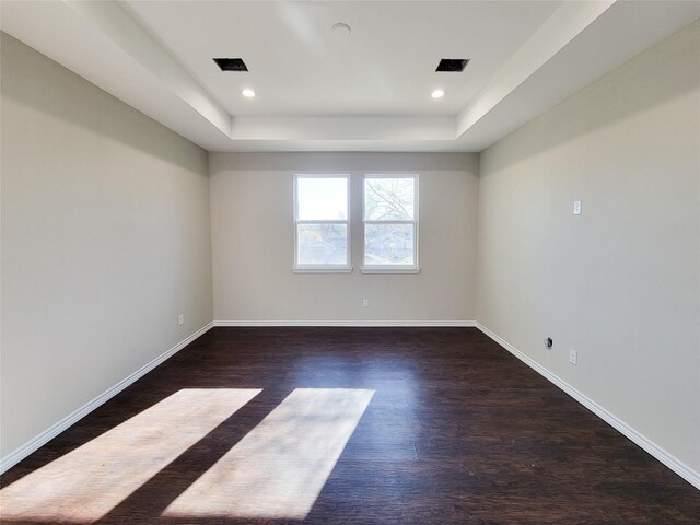 unfurnished room with a raised ceiling and dark hardwood / wood-style flooring