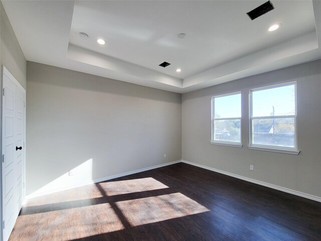 unfurnished room with dark hardwood / wood-style flooring and a raised ceiling